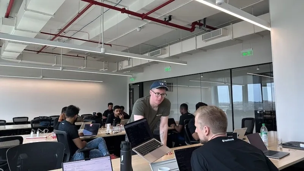 Kieran discussing a project with a coworker in person while sharing his laptop screen